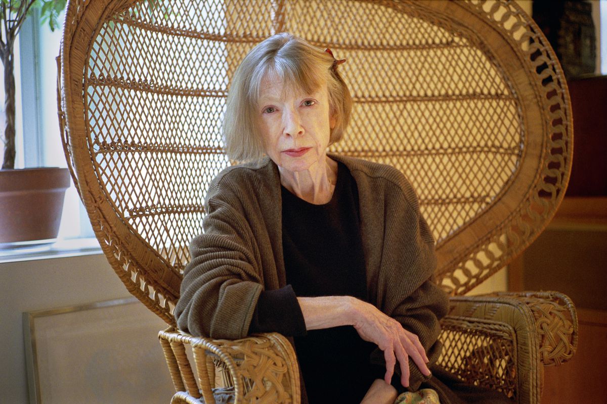 Writer Joan Didion sitting in a wicker peacock chair.
