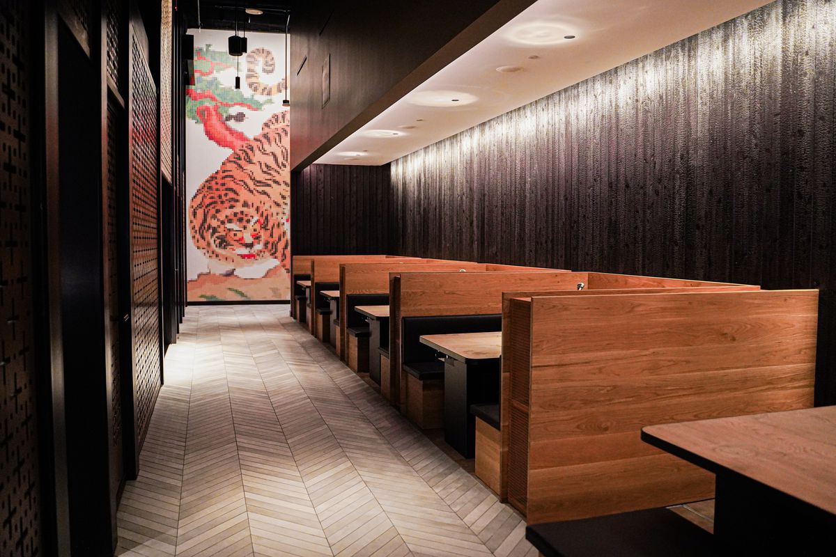 Wooden booths, a black wall, and a picture of a tiger on the wall.