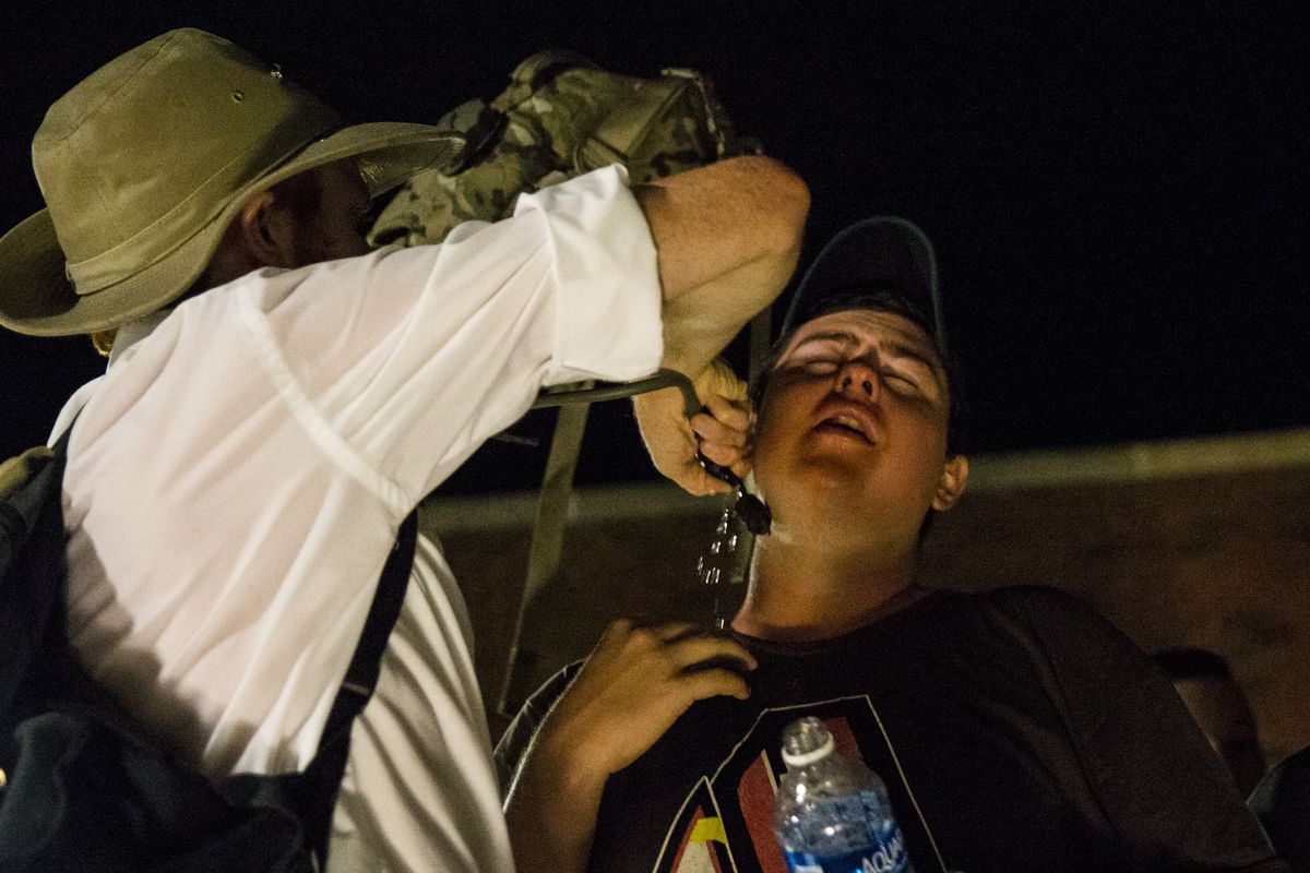 In Charlottesville, a white supremacist protester helps another after he was hit by pepper spray.