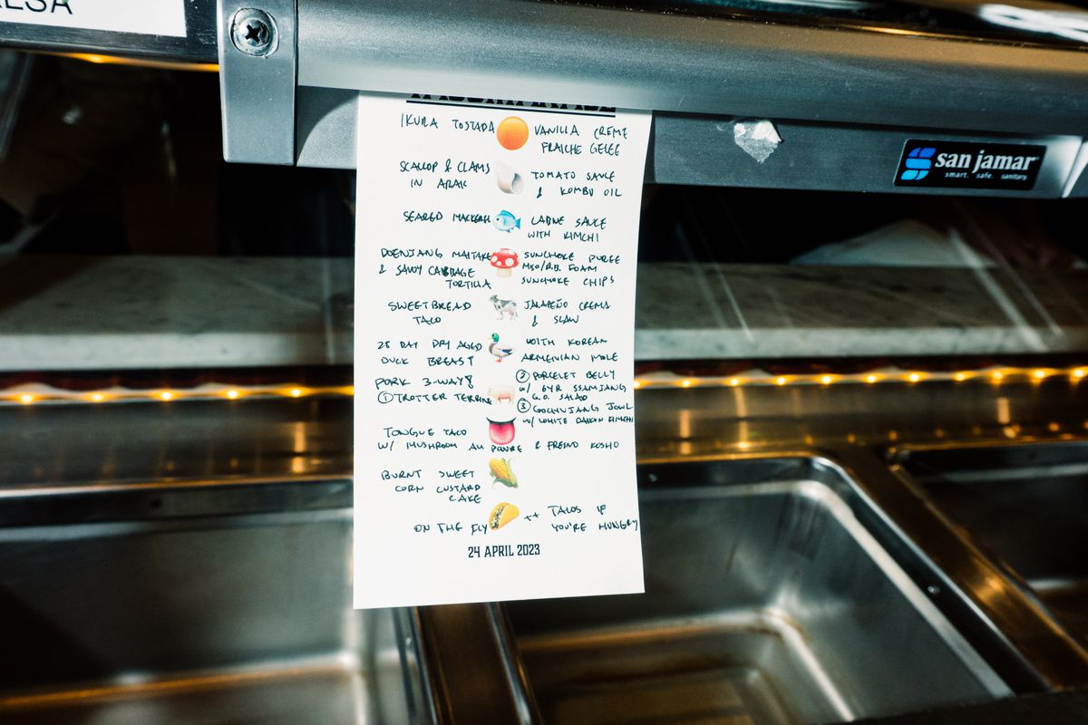 A photograph of a menu with emojis and notes from a chef.