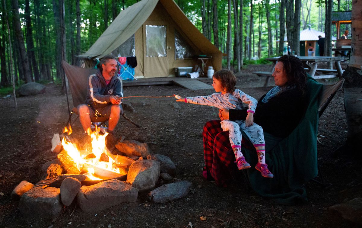 A family around a campfire with a tent