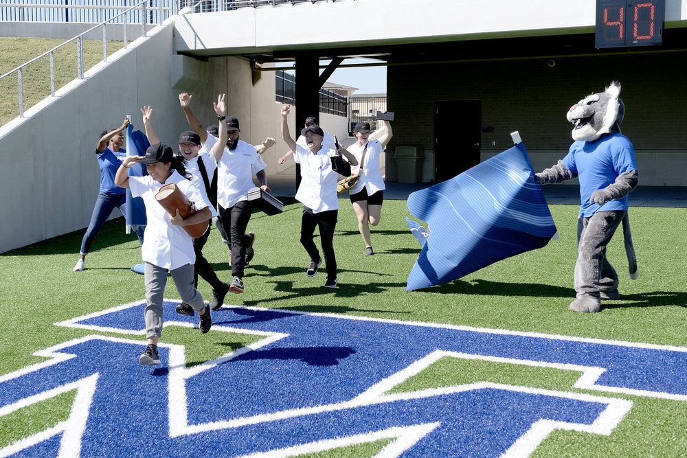 “Top Chef: Houston” contestants run on Tomball ISD’s high school stadium turf with their team mascot — a large wildcat.