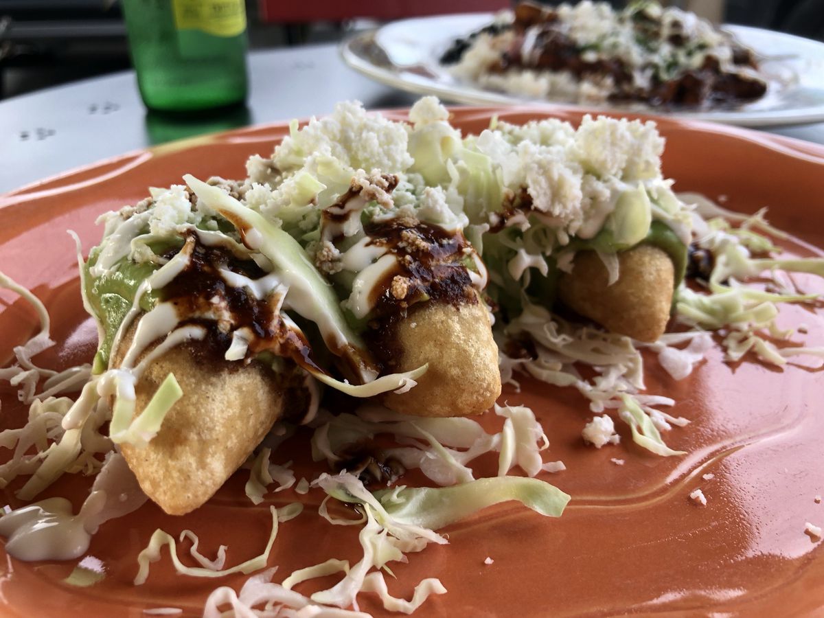 Molotes (fried corn dough dumplings) drizzled with red and green salsa and topped with cabbage and cheese.