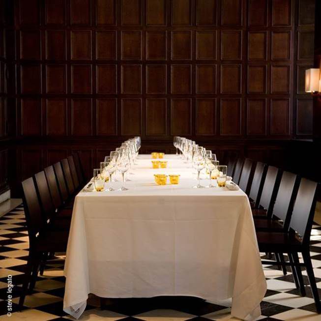 a long dining table with black chairs and a black and white checked floor