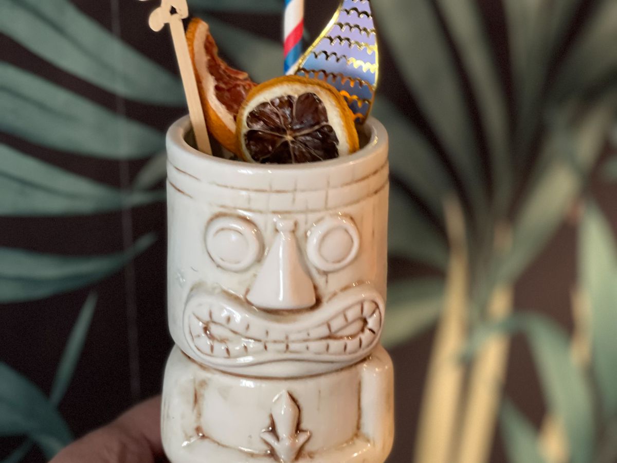 A festive tiki drink in front of tropical wallpaper
