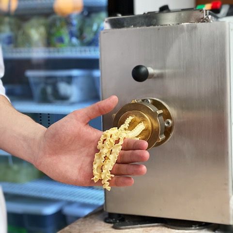 Hand collecting homemade pasta from machine