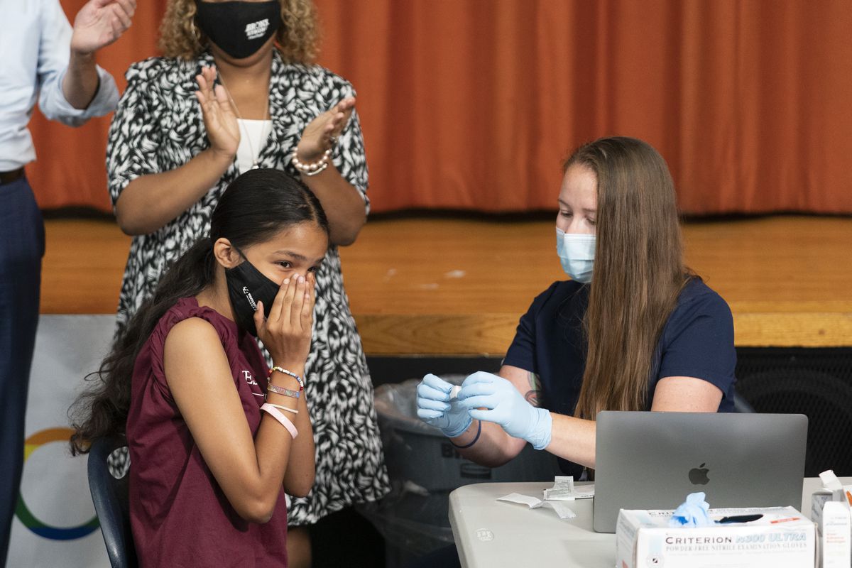Ariel Quero, 16, left, a student at Lehman High School, reacts after getting the Pfizer COVID-19 vaccine from Katrina Taormina, right, July 27, 2021, in New York. The U.S. is expanding COVID-19 boosters, ruling that 16- and 17-year-olds can get a third dose of Pfizer’s vaccine. 