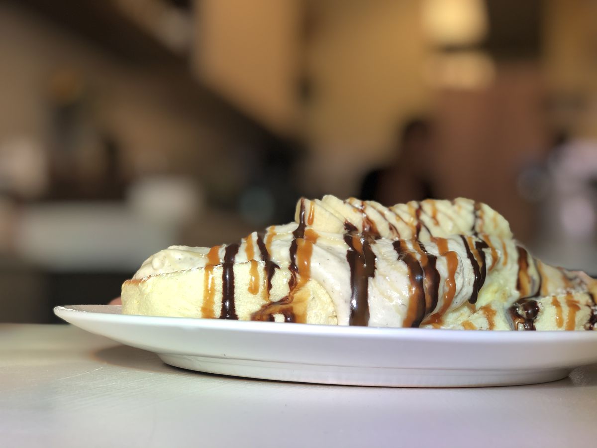 A side view shows one pancake is a couple of inches thick, topped with whipped cream and caramel and chocolate drizzles