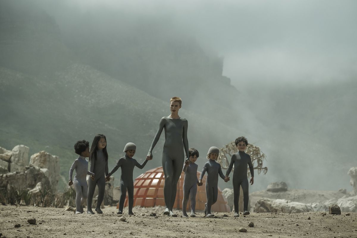 Amanda Collin leads a series of children in grey jumpsuits in Raised By Wolves