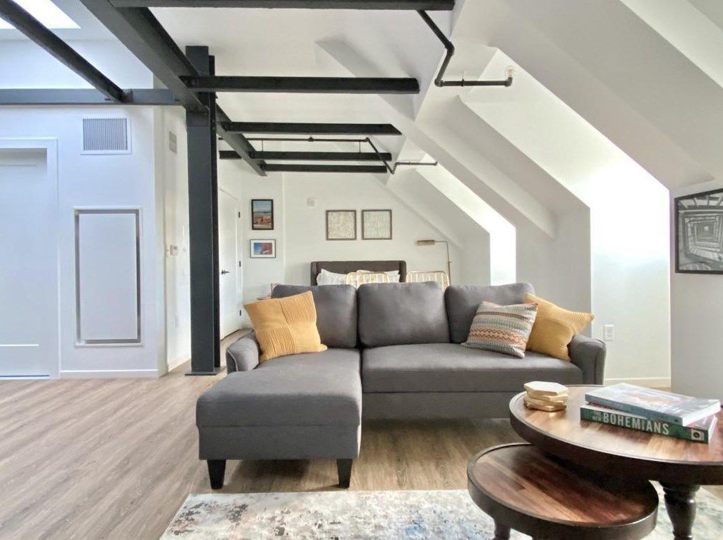 A long living room with an arched ceiling and exposed beams, and there’s an L-shaped couch.