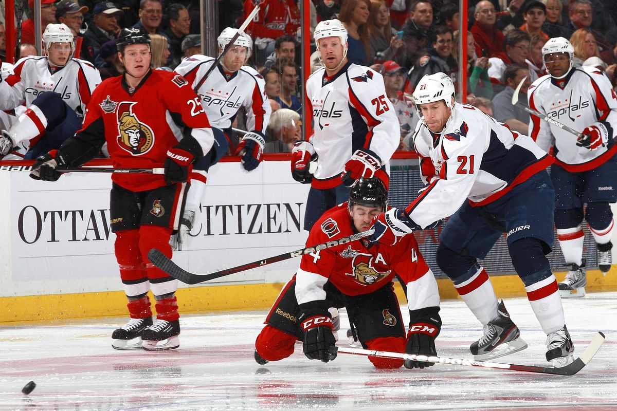 Chris Neil watches as Chris Phillips honours the terms of their bet and kisses Brooks Laich's stick mid-game.