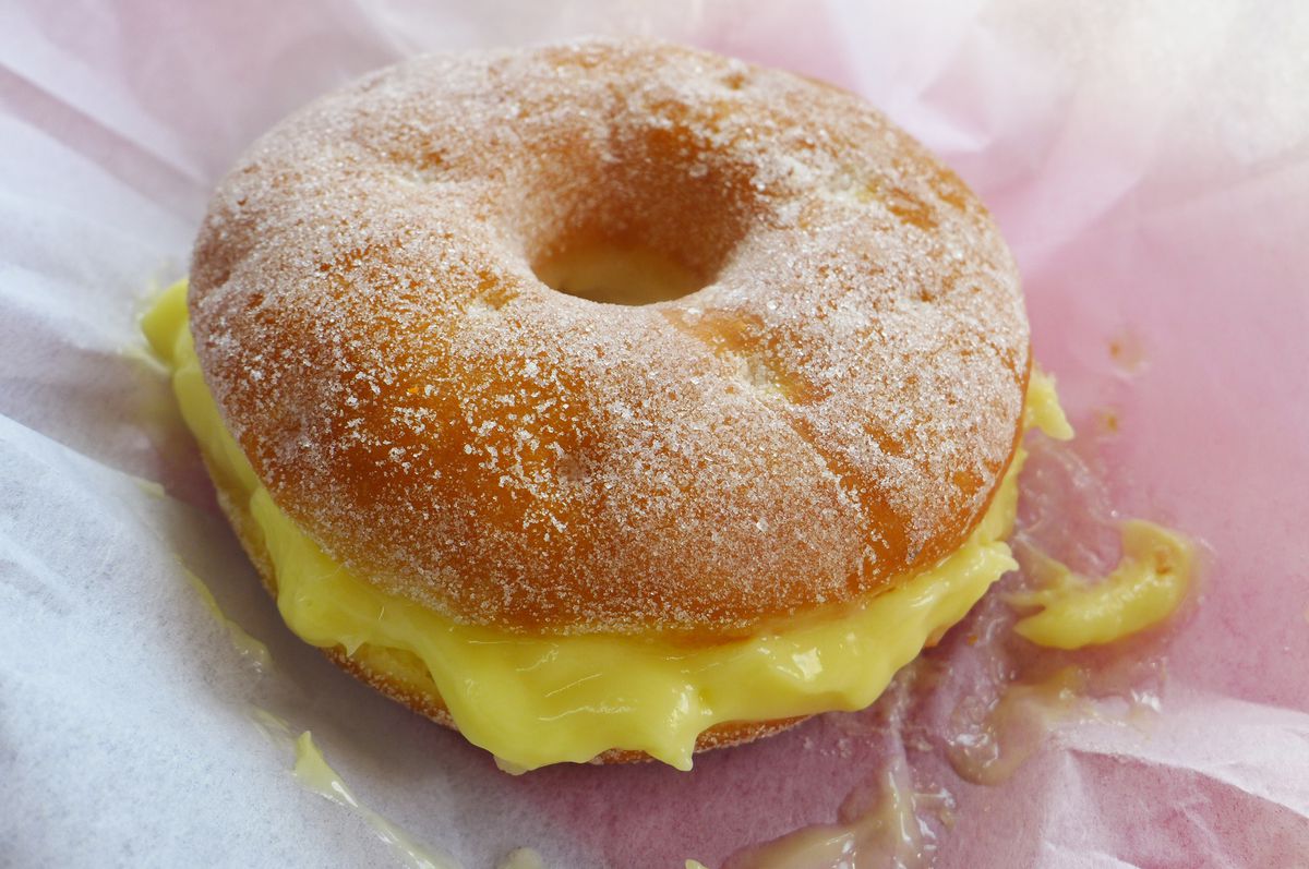 Donut split horizontally with yellow custard inside.