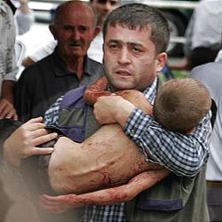 A man carries an injured child who escaped from a school Friday in Beslan, North Ossetia, after commandos stormed it.