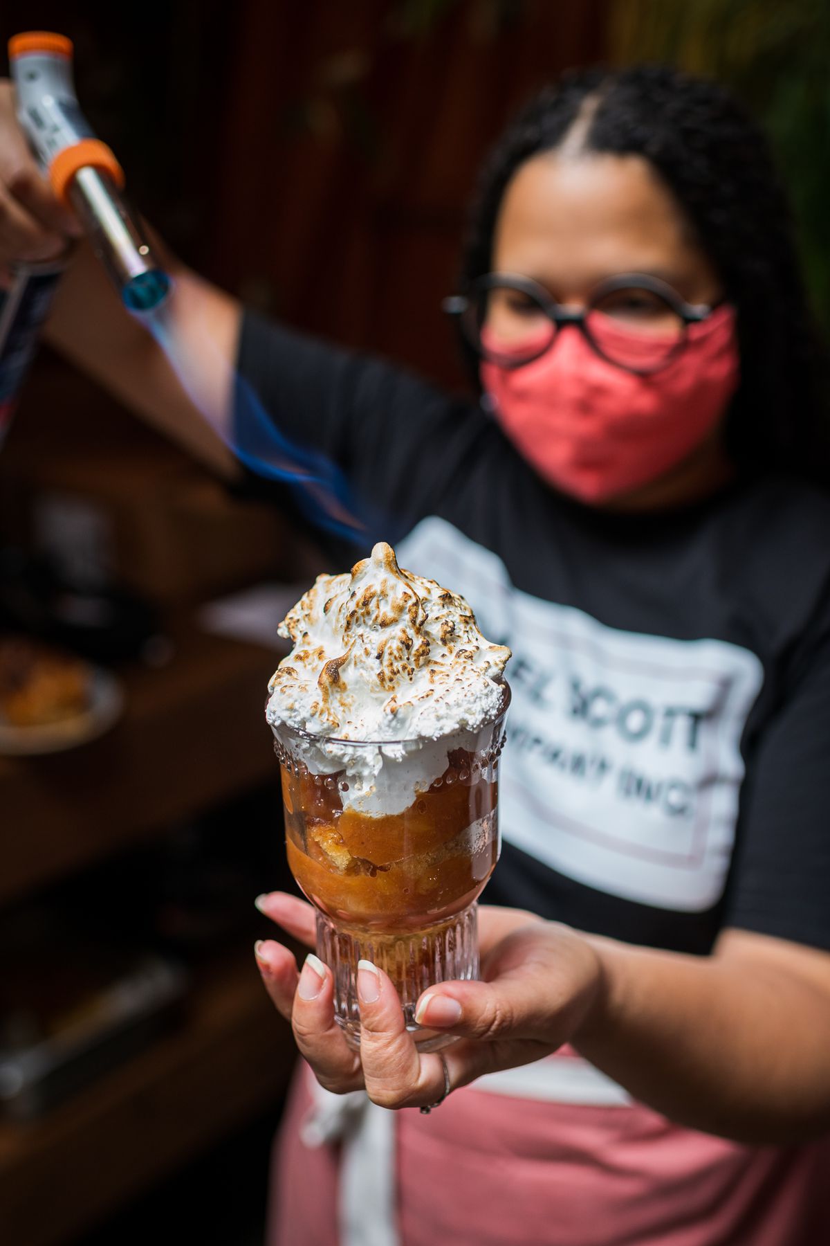Paola Velez torches a meringue topping atop a cup of bizcocho mixed with pineapple and guava jam