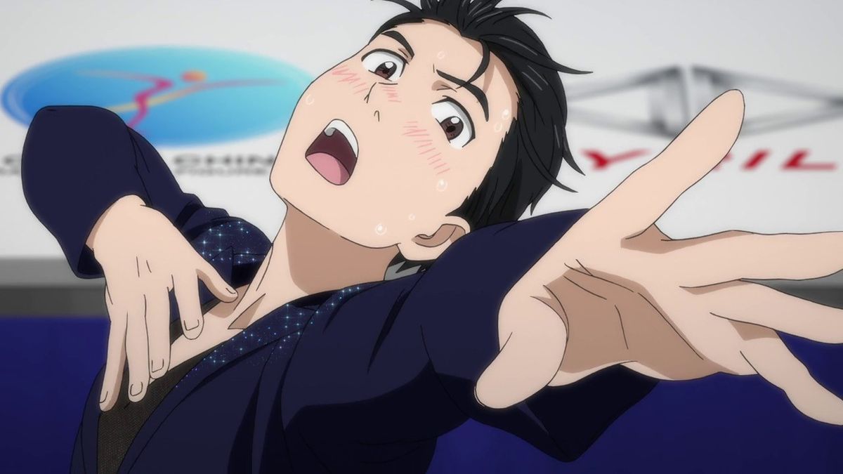 A black haired anime boy in a figure skating outfit posing dramatically with his cheeks flush with color.