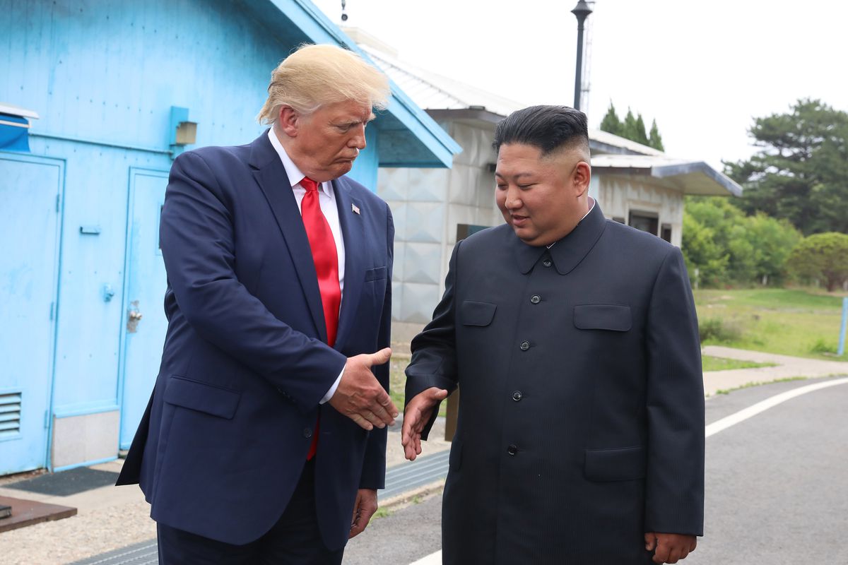 President Trump and Kim Jong Un starting to shake hands.