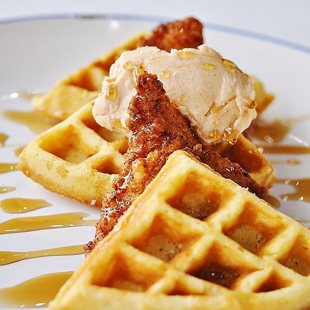 Chicken and waffles with cinnamon honey butter and maple syrup.