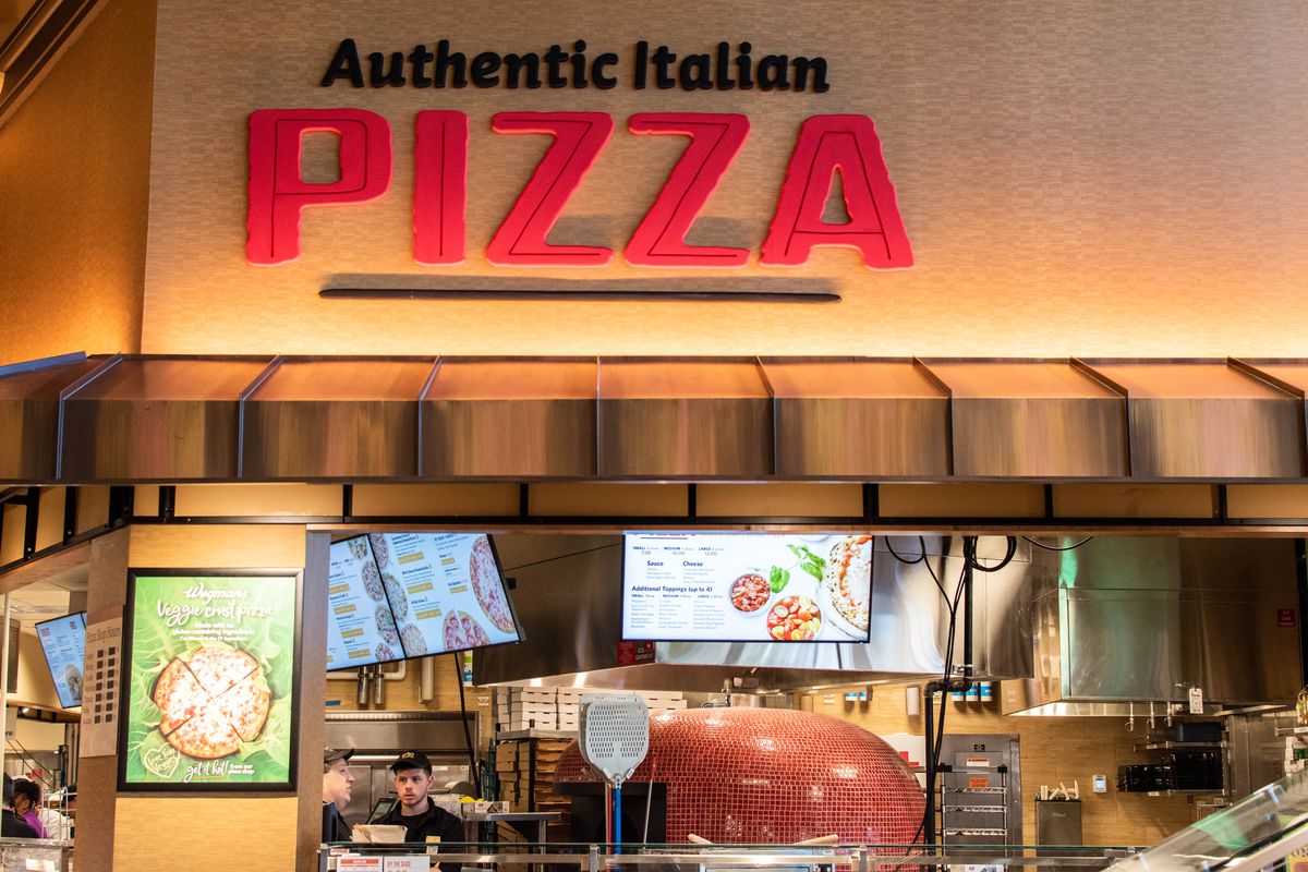 A pizza counter with a yellow sign reading “Authentic Italian Pizza”
