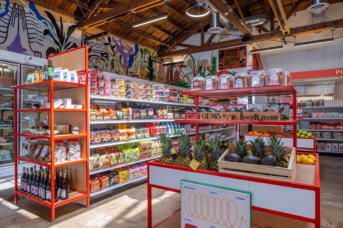 Open shelves filled with food items at a colorful grocery inside of a warehouse space.