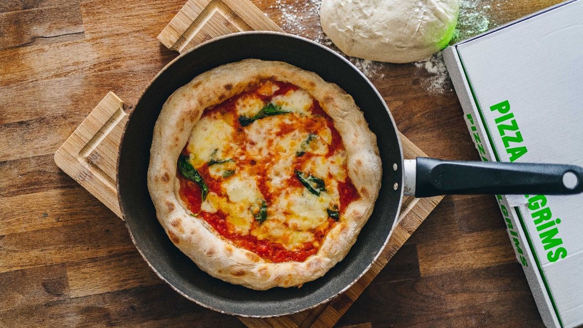 A Pizza Pilgrims frying pan pizza, a margherita in a frying pan on a wooden board