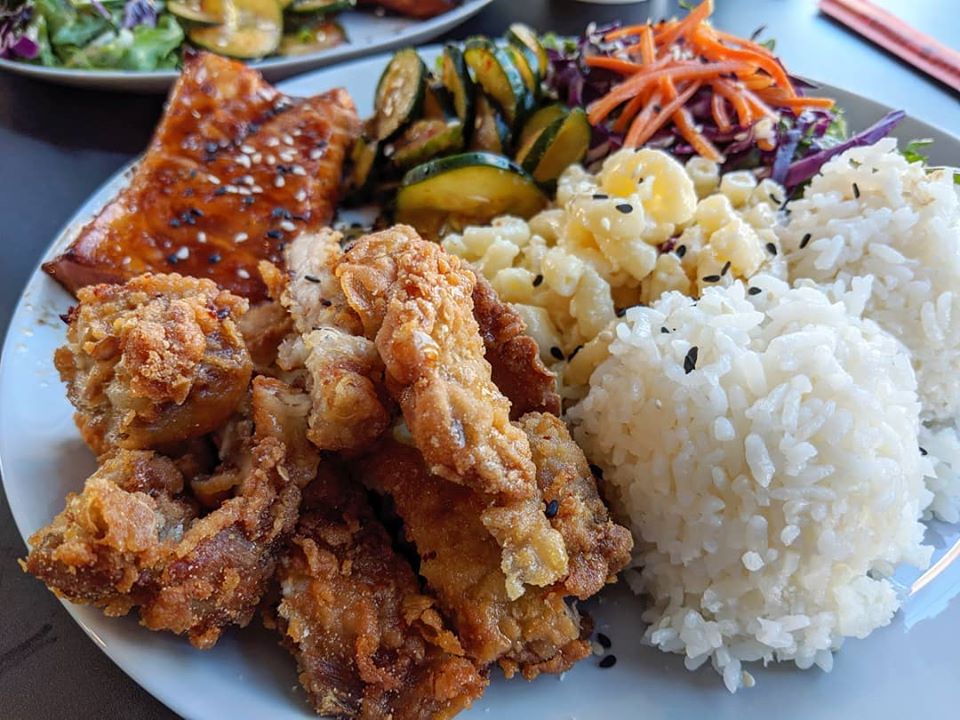 A plate of fried chicken, white rice, mac salad, kimchi, greens, and a chile-glazed piece of salmon belly