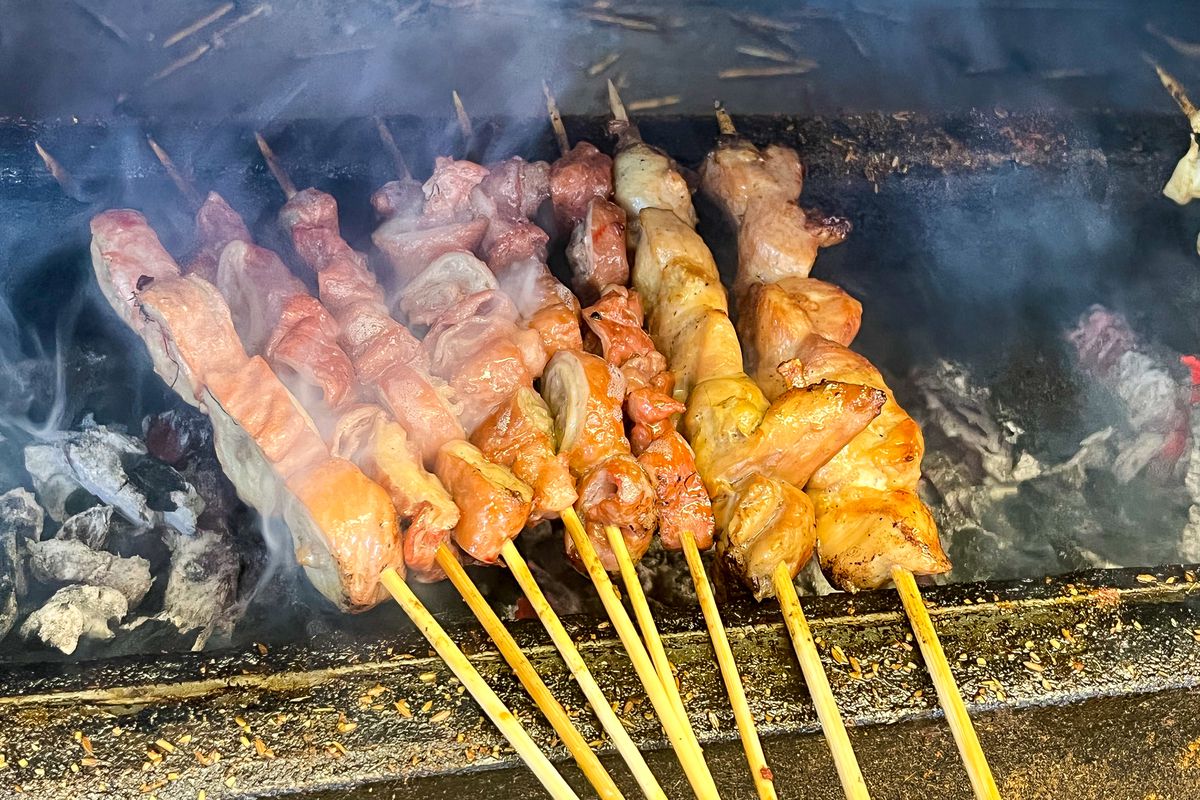 Assorted skewers are cooked on a grill.