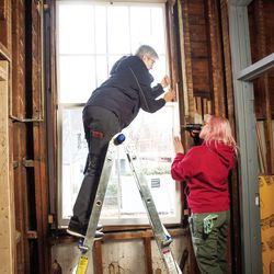 Hardy (left) and Lauren Marnik reinstall a restored double-hung window, switching out rotted ropes for sash chains, which can hold more weight and require less maintenance.