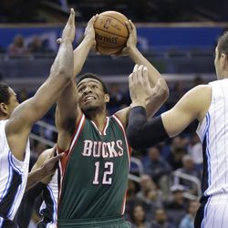 Milwaukee Bucks' Jabari Parker (12) goes up for a shot as he gets between Orlando Magic's Channing Frye (8) and Nikola Vucevic (9) during the first half of an NBA basketball game in Orlando, Fla., Friday, Nov. 14, 2014. (AP Photo/John Raoux)
