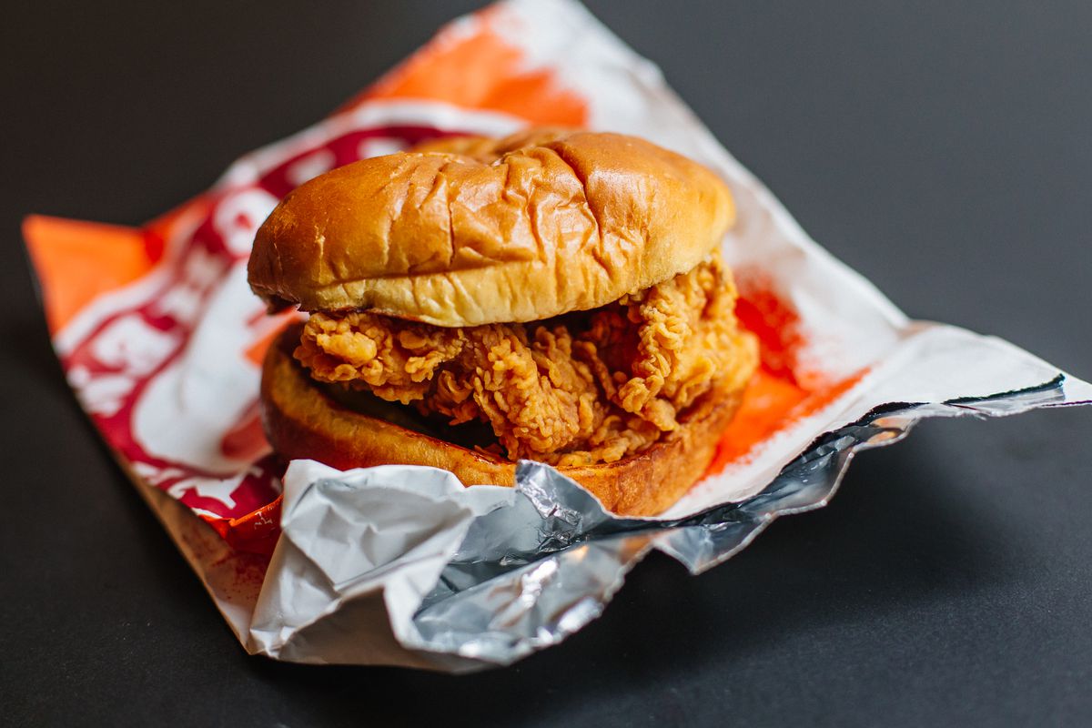 A fried chicken sandwich sitting on top of a Popeyes foil bag.