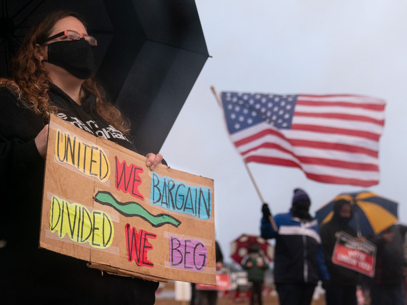 A protester holds a sign near Amazon’s Bessemer, Alabama, warehouse that reads, “United we bargain, divided we beg.”