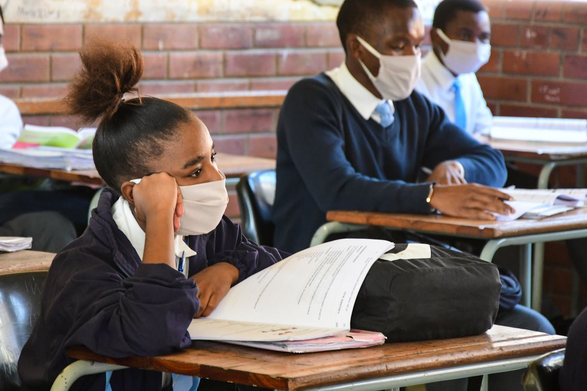 A student in a face mask sitting at a school desk with her head propped on her fist, Durban, South Africa, June 9, 2020.