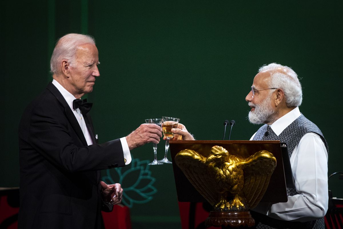 Biden and Modi tap drink glasses together in a cheers.