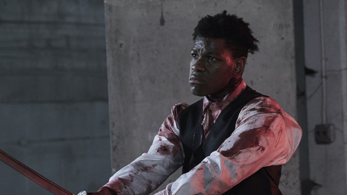 A blood-covered John Boyega looks oddly solemn while wielding a katana