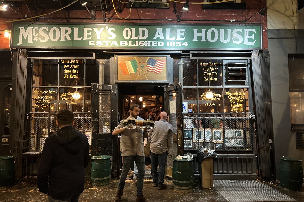 The main entrance to McSorley’s is show with a worker leaving with multiple beer mugs