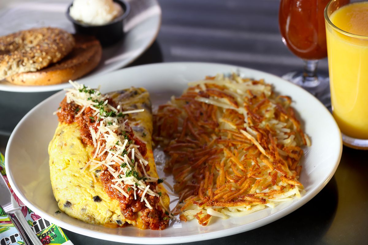 An omelet topped with sauce and a side of hash browns.