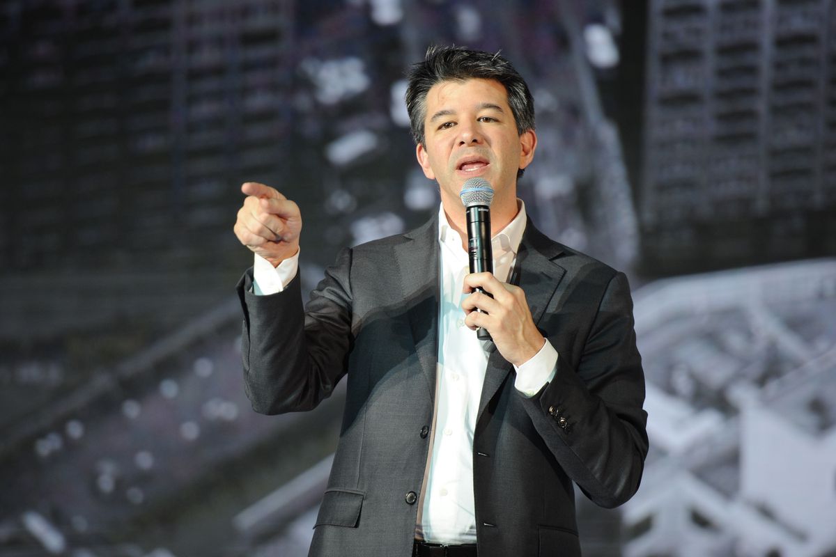 Former Uber CEO Travis Kalanick onstage holding a microphone and pointing at the audience