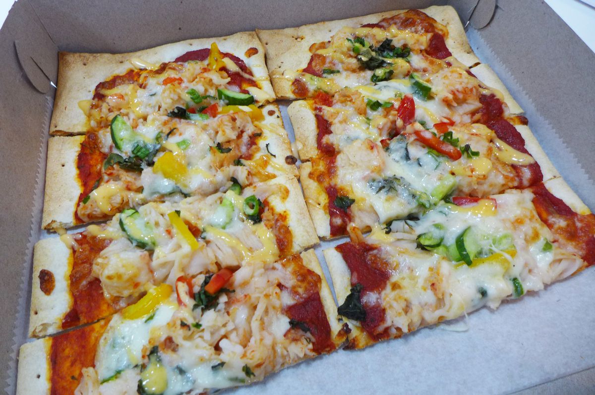 A rectangular pizza cut into eight pizzas with red and white and yellow visible on top, and in a box.