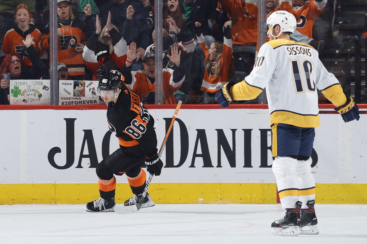 Joel Farabee skates with his right arm up in the air in celebration after scoring a goal. Predators skater Colton Sissons is framed in the shot as well, his back turned to the camera