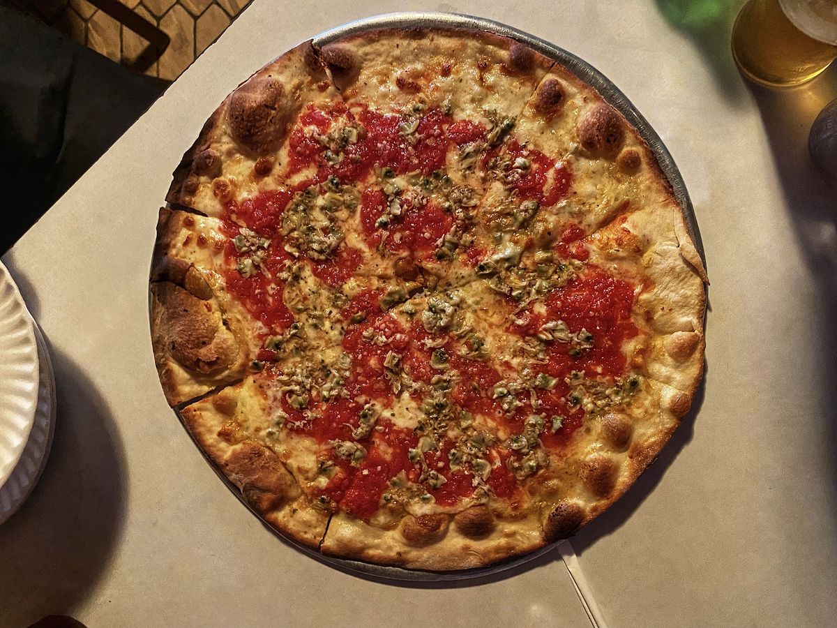 An overhead photograph of a red sauce pizza with minced clam strewn on top.