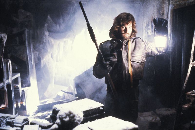 Kurt Russell holds up a lantern in a frosty room