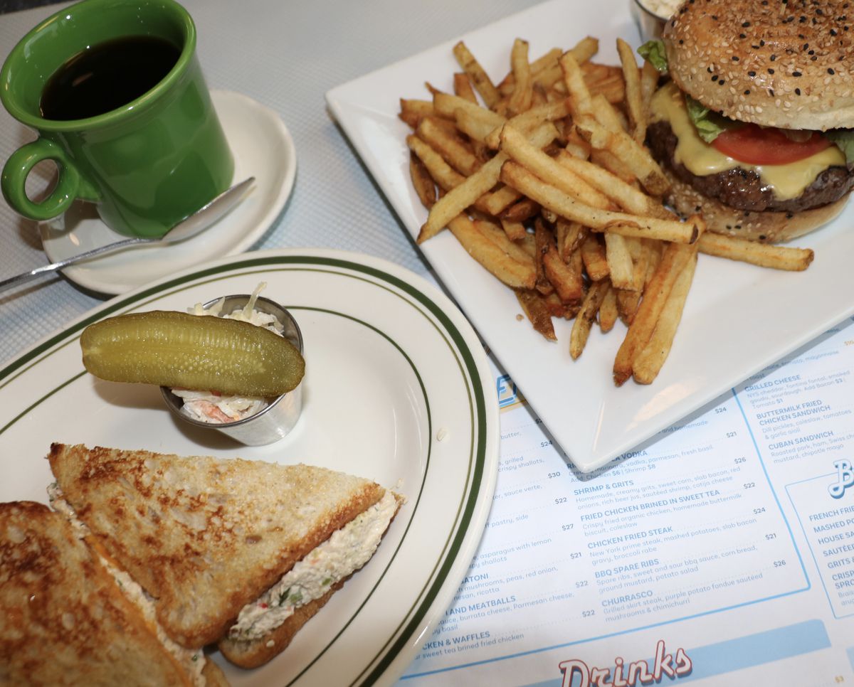 A table with french fries, a tuna melt, and a burger.