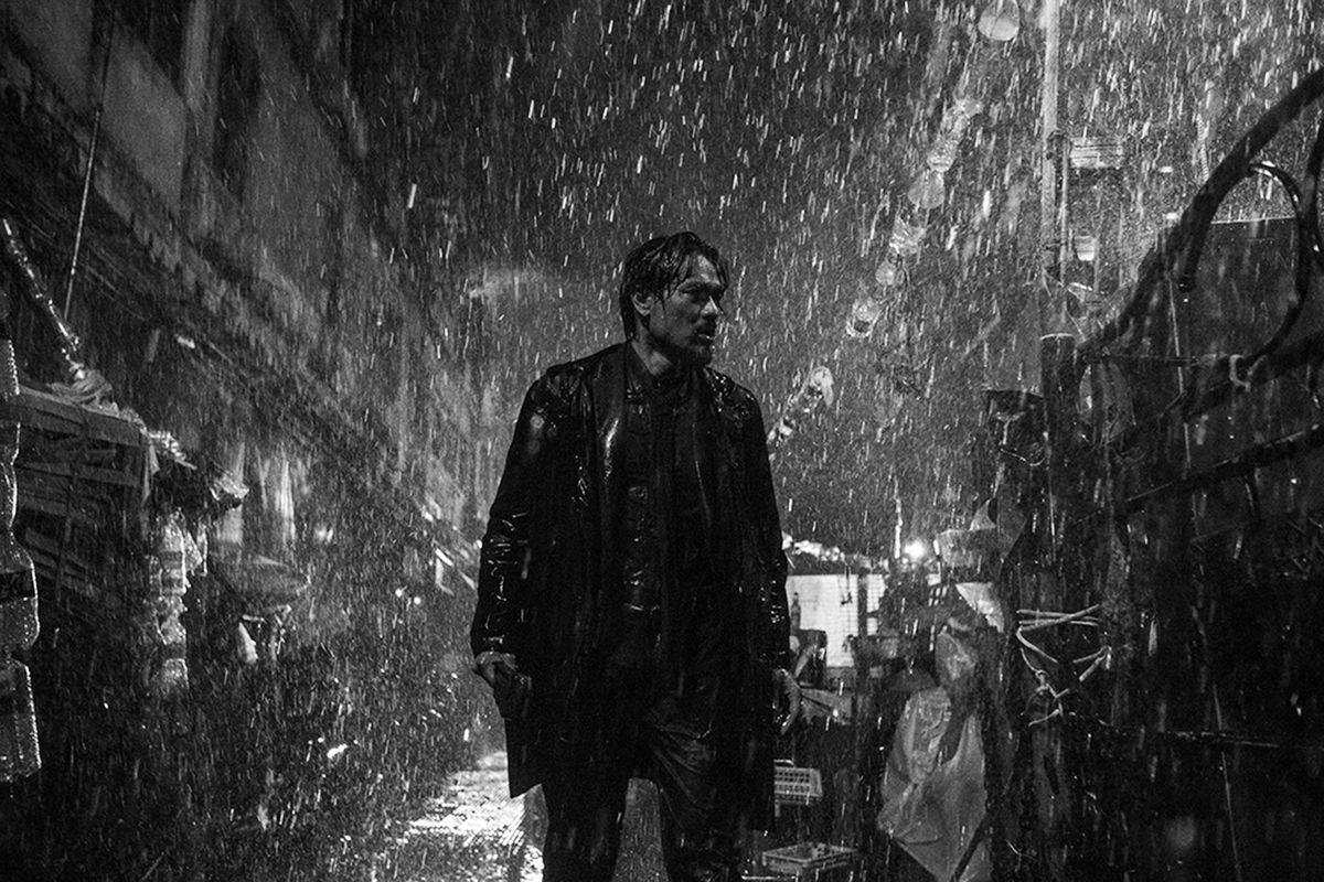 A man walks through a narrow, rainy street, in a black-and-white image from Limbo.