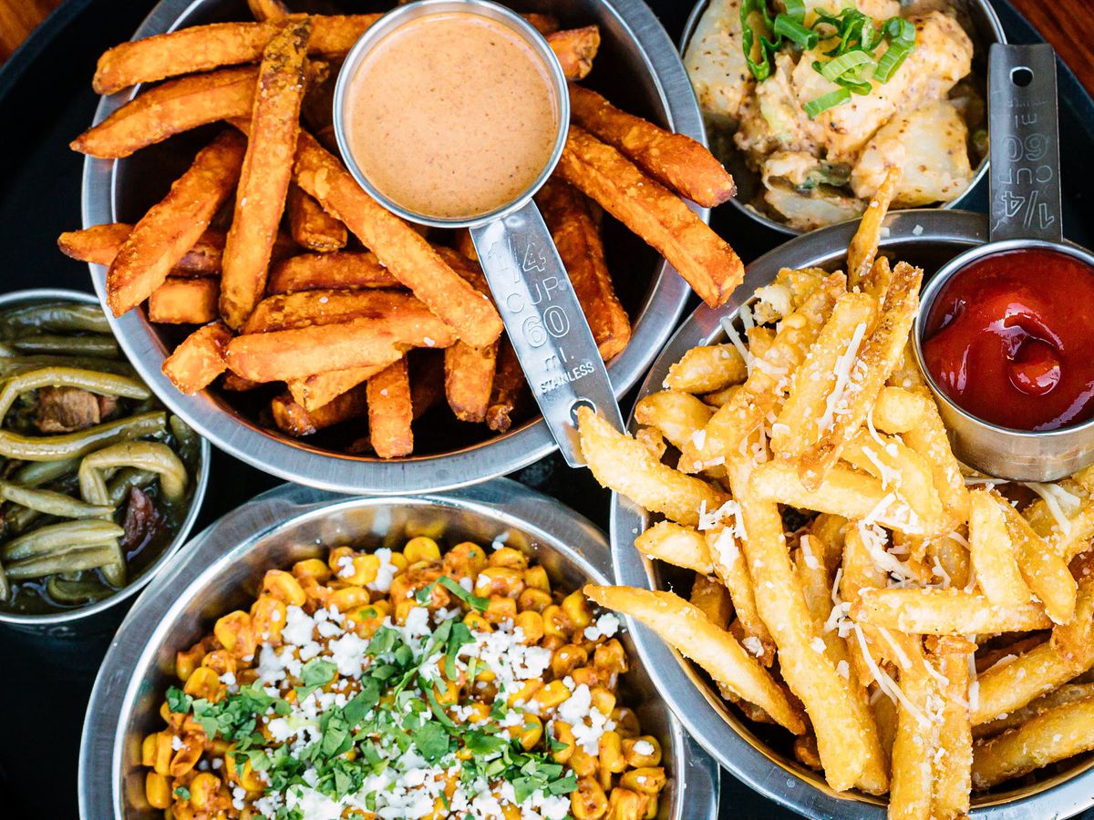 Three metal bowls, two with fries and the other with corn.