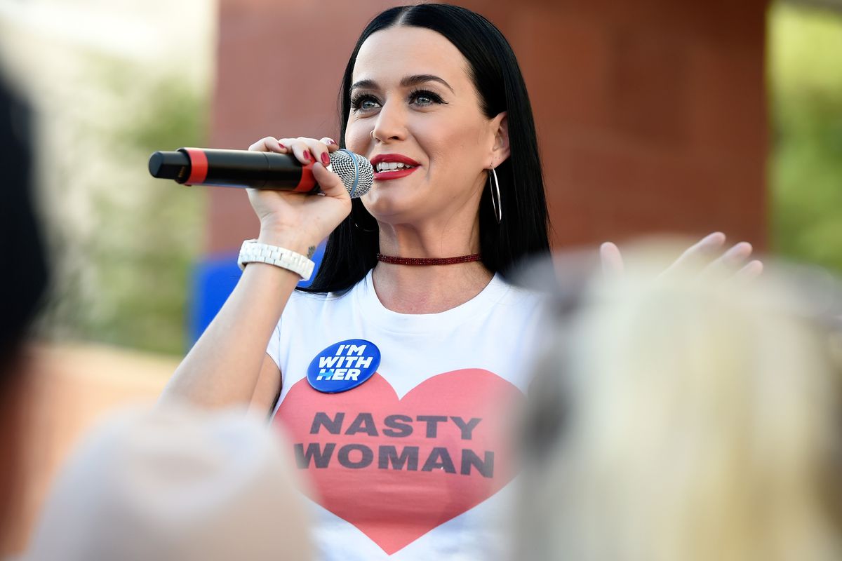Katy Perry wearing a “Nasty Woman” shirt while speaking into a mic at a political rally