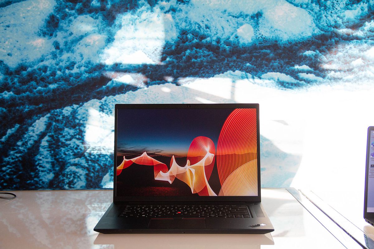 The Lenovo ThinkPad X1 Extreme open on a white table. The screen displays a desert night scene with a bright orange ribbon running through it.