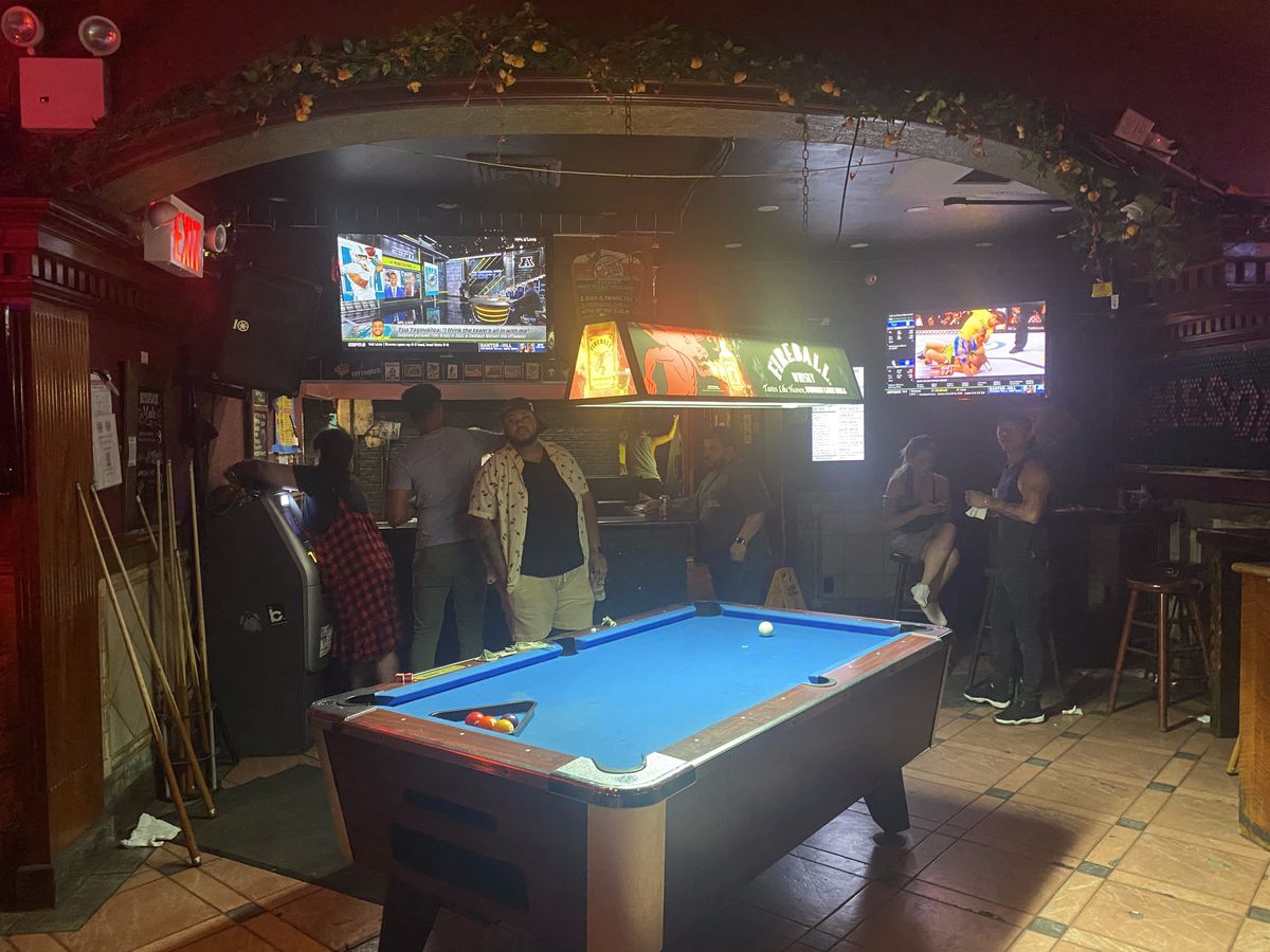 Customers crowd around a pool table at a Brooklyn dive bar, Alligator Lounge.