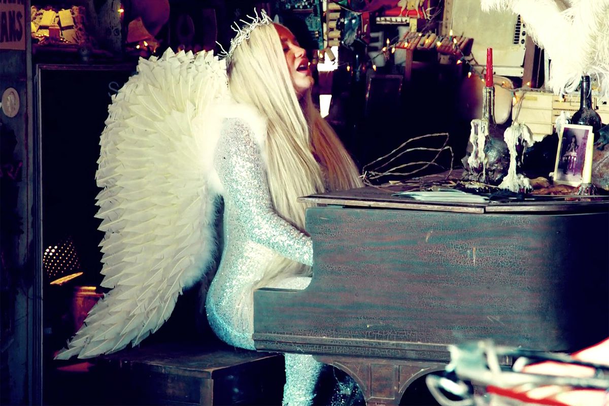 Kesha wears a custom Queenie Cao jumpsuit and vintage angel wings from Palace Costume in her “Praying” music video.
