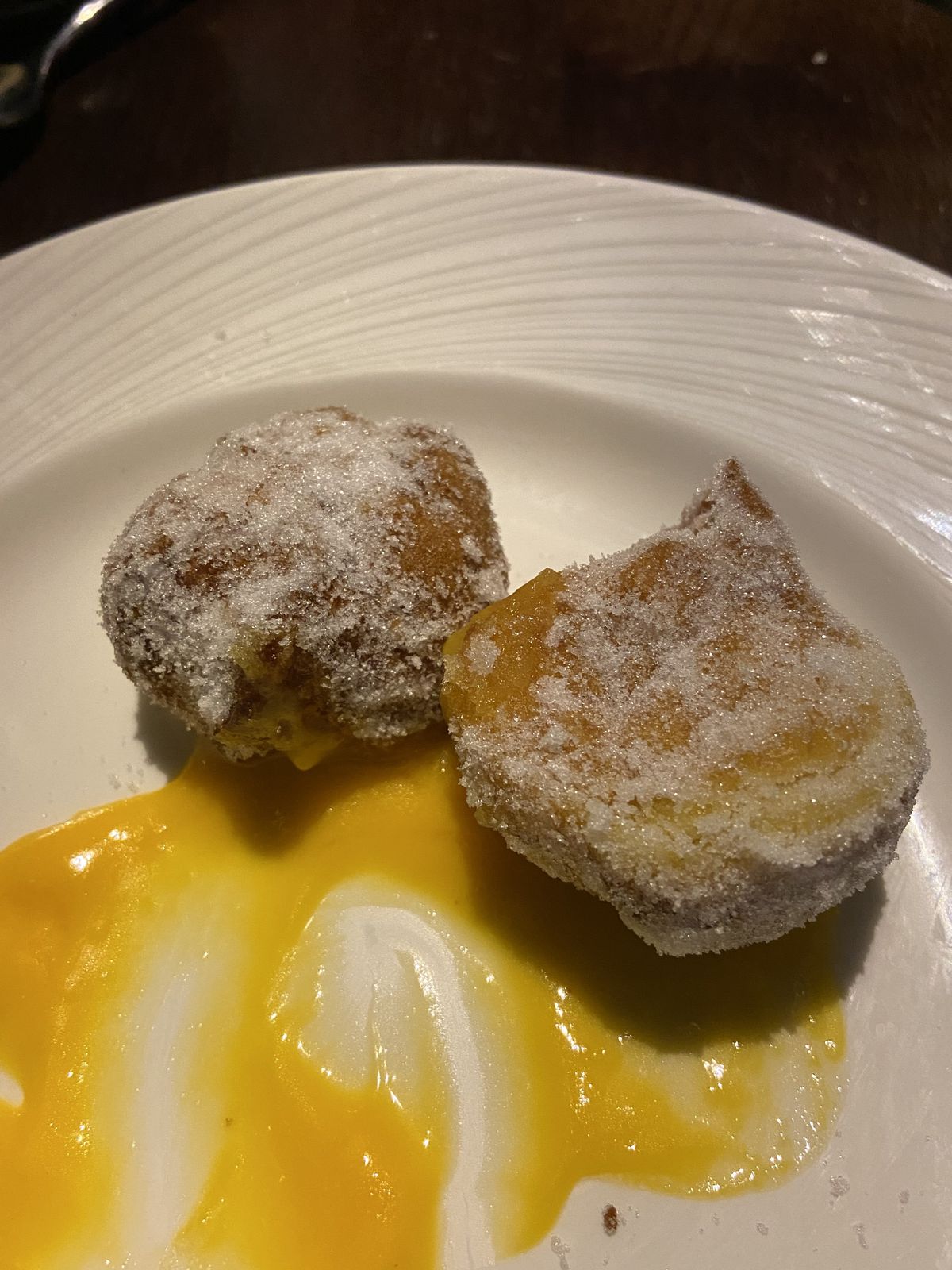 Two passionfruit beignets with a velvety fruit curd smeared across the plate at 7 Saints.  