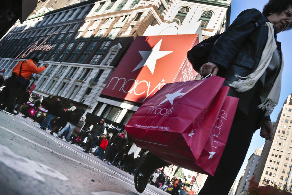 This Nov. 23, 2013 file photo shows a shopper carries Macy's bags while crossing an intersection outside Macy's in New York. Shopping for Black Friday started early this year. The annual shopping frenzy is seemingly replacing the Thanksgiving emphasis on 