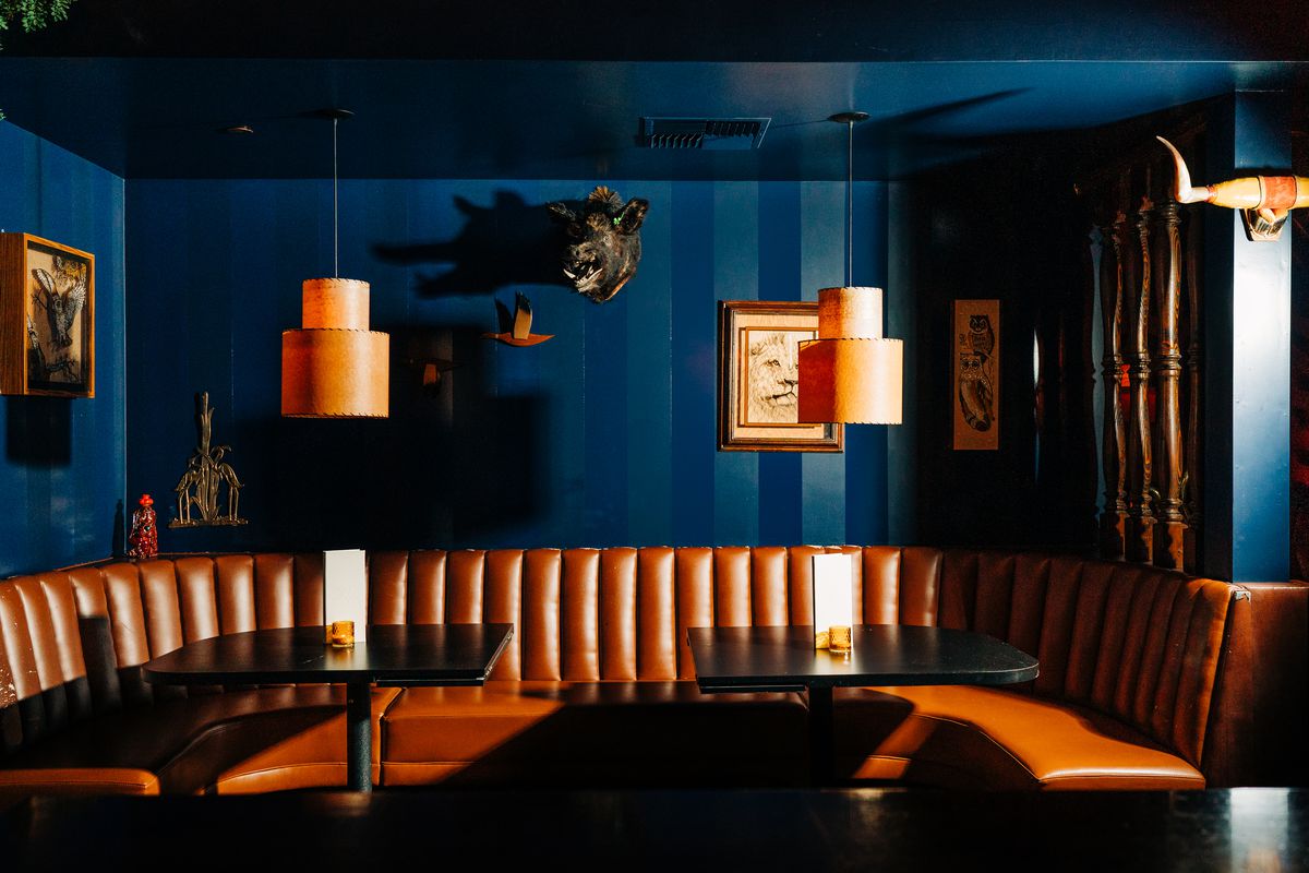 A tan leather booth under a blue wall decorated with stuffed animal heads.